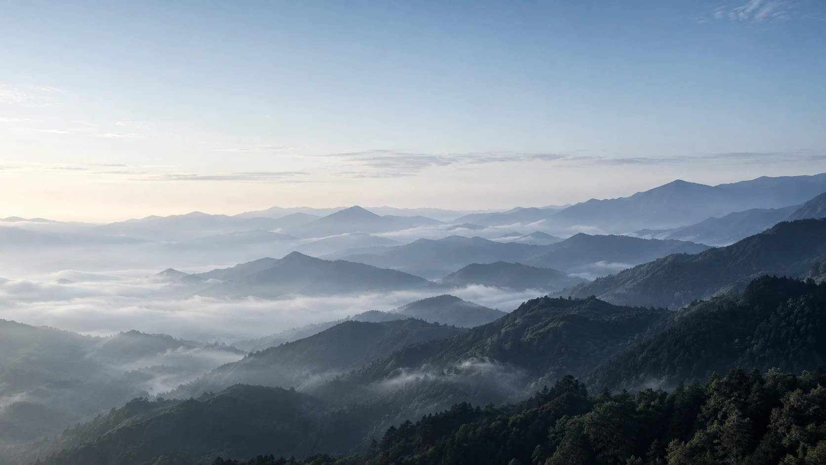 朝の光と霧に包まれた山並みのイメージ